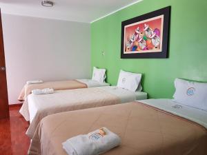 three beds in a room with green walls at Hotel Luz de Luna in Atico