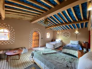 a bedroom with two beds in a room with wooden ceilings at Camp Auberge Sahara Marokko in Mhamid