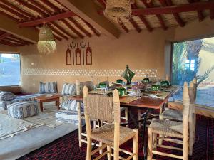 a dining room with a wooden table and chairs at Camp Auberge Sahara Marokko in Mhamid
