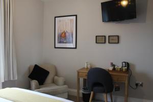 um quarto com uma cadeira, uma secretária e uma televisão na parede em The Hill B&B em Middleton in Teesdale