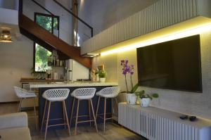 una cucina con bar con sgabelli e TV di Bosque da Praia 22 Premium a Pipa