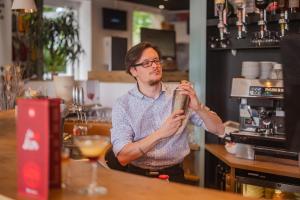 Ein Mann, der an einer Bar sitzt und einen Drink hält. in der Unterkunft ibis Colmar Est - Hotel Restaurant en Alsace in Colmar