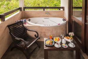 Zimmer mit einer Badewanne, einem Stuhl und einem Tisch in der Unterkunft Terrace Green Hotel & Spa in Negombo