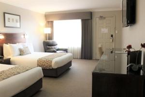 a hotel room with two beds and a television at Carlyle Suites & Apartments in Wagga Wagga