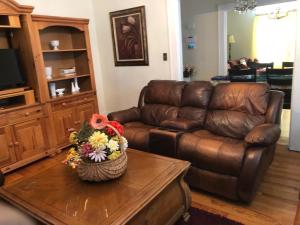 a living room with a leather couch and flowers on a table at Brick House Retreat in Rockingham