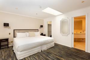 Fino Hotel & Suites في كرايستشيرش: غرفة نوم بسرير ابيض كبير وحمام