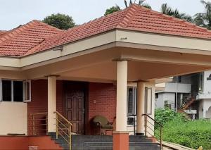 una pequeña casa roja con techo rojo en Tharavad Holiday Home, en Mangalore