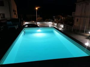 Una piscina con iluminación azul en un techo por la noche. en Alcamo Marina Villa Pool, en Alcamo Marina