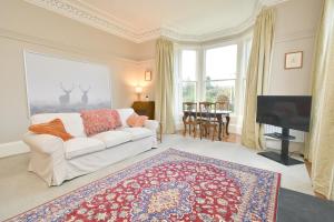 een woonkamer met een witte bank en een televisie bij West Deyne in Dundee