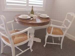 a table with two chairs and a bottle of wine at Chez Vous French Farmhouse Villa 4 in Pokolbin