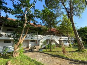 an exterior view of a white building with trees at Duenshine Resort in Kanchanaburi