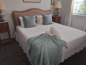 um quarto com uma cama com um cobertor e almofadas em Chez Vous French Cottage - Pokolbin Hunter Valley! em Pokolbin