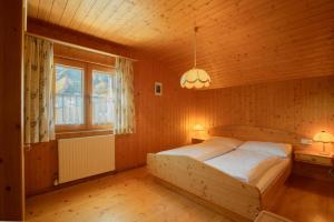 ein Schlafzimmer mit einem Bett in einem Holzzimmer in der Unterkunft Lari Fari in Faschina