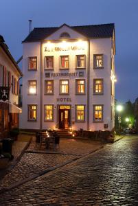 un hotel se ilumina por la noche en una calle adoquinada en Zur Ewigen Lampe Romantisches Landhotel & Restaurant, en Nideggen