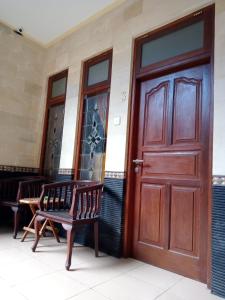 a wooden door of a building with two chairs at Cempaka 2 Homestay in Legian