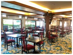a dining room with tables and chairs and windows at Dad D Resort by Lopburi Inn Resort in Lop Buri