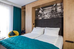 a bedroom with a bed with a green and white comforter at Das Steinmüller Hotel in Gummersbach