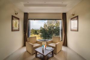 uma sala de estar com uma mesa e cadeiras e uma grande janela em Savitri Resort em Pushkar