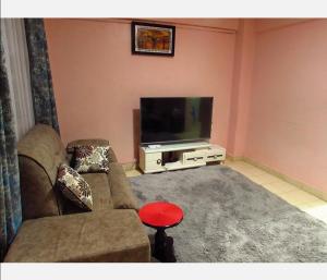 ein Wohnzimmer mit einem Sofa und einem Flachbild-TV in der Unterkunft Tazama place in Nyeri