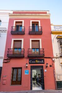 a red brick building with a red door and windows at Cool Sevilla Hotel in Seville