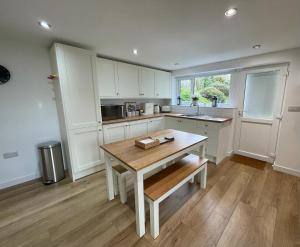 una cucina con armadi bianchi e tavolo in legno di Lovely ground floor apartment in quiet village a Exeter