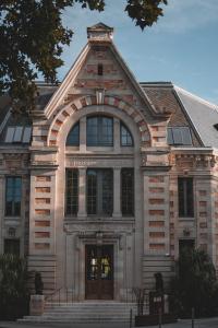 Hotel La Zoologie & Spa Bordeaux في بوردو: مبنى من الطوب كبير مع قوس على الباب