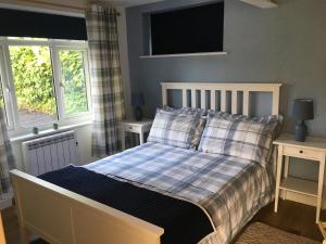 a bed in a bedroom with two windows at Lovely ground floor apartment in quiet village in Exeter