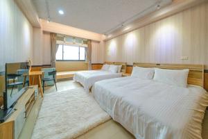 um quarto de hotel com duas camas e uma televisão em 鼎愛溫泉行館 em Jiaoxi