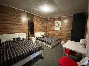 a bedroom with two beds and a table and a desk at Hostel Piaseczno in Piaseczno