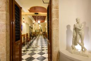 Eine Statue eines Mannes an einer Wand im Flur. in der Unterkunft Halepa Hotel in Chania