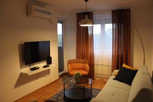 a living room with a white couch and a tv at Luxury apartments Free Parking in Niš