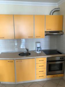 a kitchen with yellow cabinets and a sink at Family Apartment & Outside Pool in Savudrija