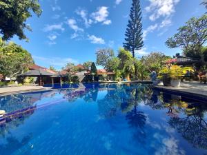 a pool at a resort with blue water and trees at Puri Bali Hotel in Lovina