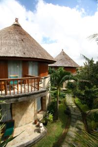 una casa con techo de paja y pasarela en Dewani Villa Resort, en Canggu