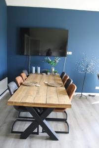een eettafel met stoelen en een blauwe muur bij BakBoord in Grou