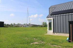 a house with a large field next to a building at BakBoord in Grou