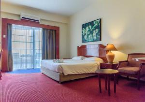 une chambre d'hôtel avec un lit et une chaise dans l'établissement J Beach Suites At Rainbow Paradise, à Tanjung Bungah