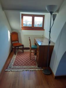 an attic room with a desk and a chair and a lamp at B&B Villa Acacia in Kapellen