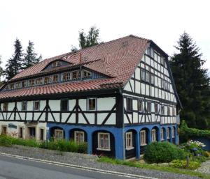 a house with a tiled roof on the side of the road at Haus zur alten Bimmelbahn in Kurort Jonsdorf