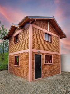 uma casa de tijolos vermelhos com uma porta e janelas em Las del Tatu em El Bolsón