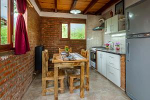 cocina con mesa de madera y pared de ladrillo en Las del Tatu en El Bolsón