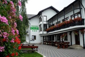 ein Gebäude mit Bänken und Blumen im Innenhof in der Unterkunft Pensiunea Indra in Gura Humorului