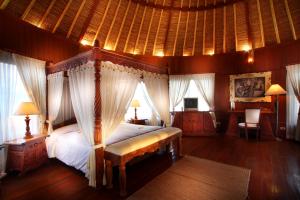 a bedroom with a canopy bed in a room with windows at Dewani Villa Resort in Canggu