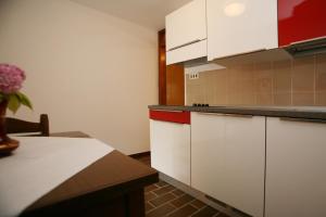 a kitchen with white cabinets and a vase of flowers at Apartments Neda - Poreč South in Poreč