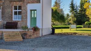 een stenen huis met een groene deur en een trap bij Ferienwohnung am Froser See in Frose