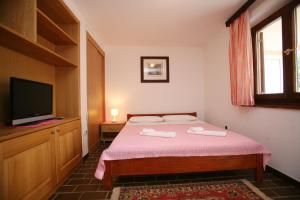a bedroom with a bed and a flat screen tv at Apartments Neda - Poreč South in Poreč