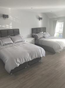 two beds in a bedroom with white walls and wood floors at Modern 3-Bed Apartment in Magherafelt Sleeps 8 in Magherafelt
