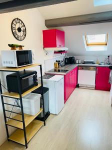 a kitchen with red cabinets and a clock on the wall at le Seize B in Épernay