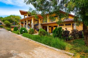una casa amarilla con un árbol y una calle en Lake Bogoria Spa Resort, en Marigat