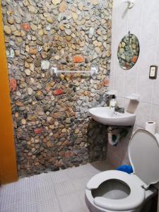 a bathroom with a stone wall and a toilet and a sink at Casa Donaji in Oaxaca City